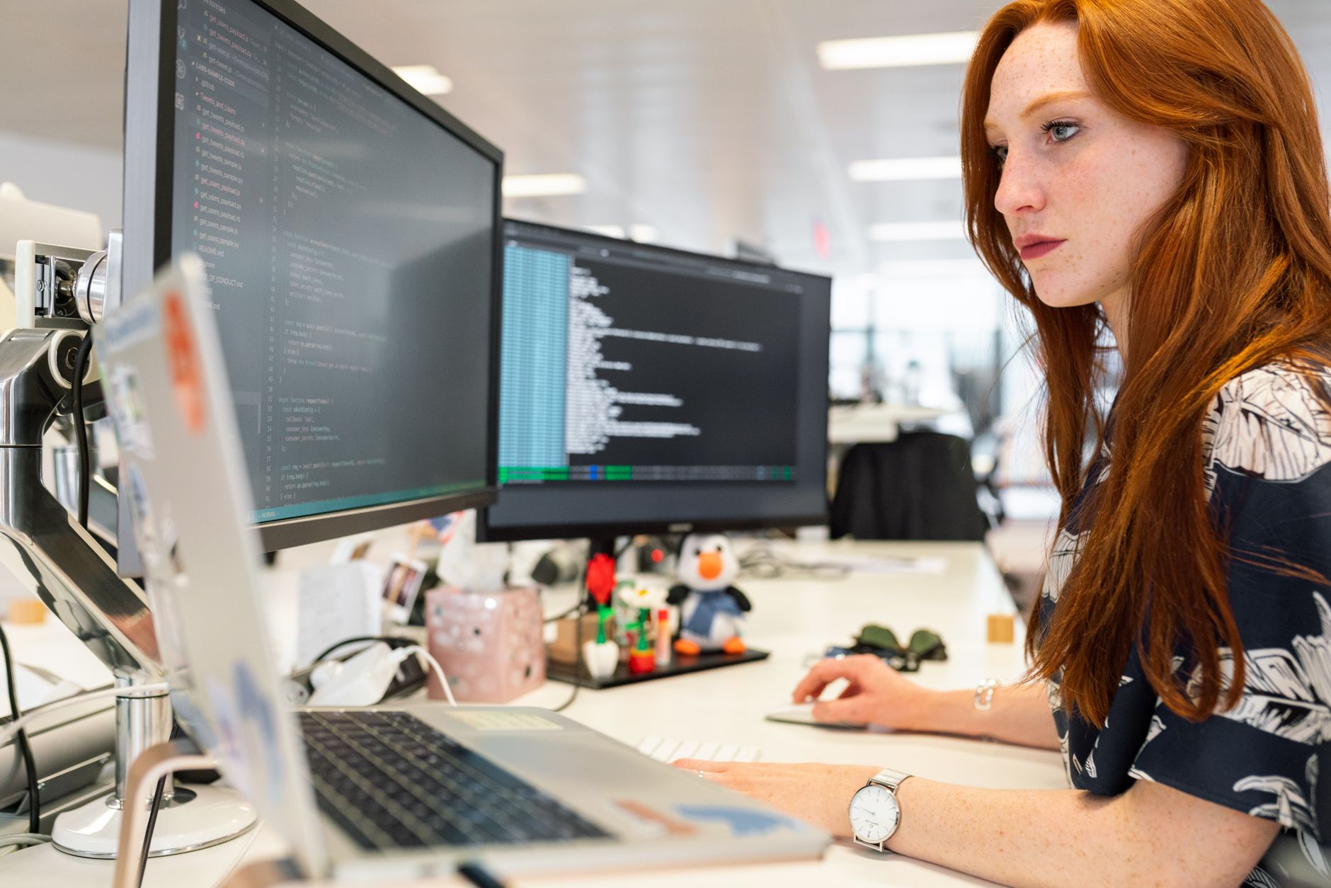 A software engineer reviewing code on two monitors.